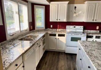remodeled kitchen with white cabinets and gray and white countertops