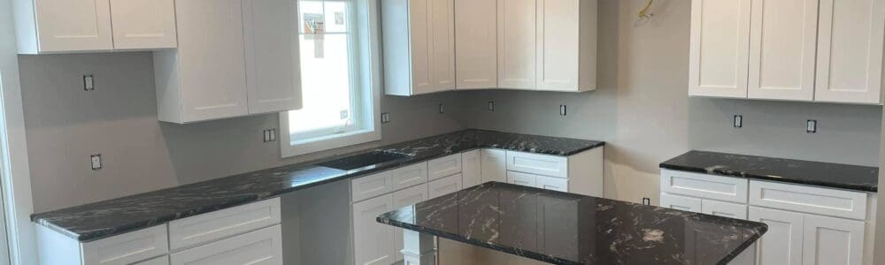 remodeled kitchen with gray walls, white cabinets, and black countertops