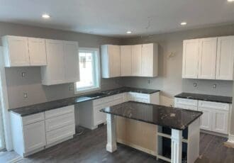 remodeled kitchen with gray walls, white cabinets, and black countertops