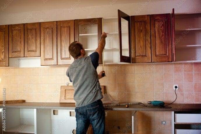 Worker measuring kitchen cabinets during a home remodeling project